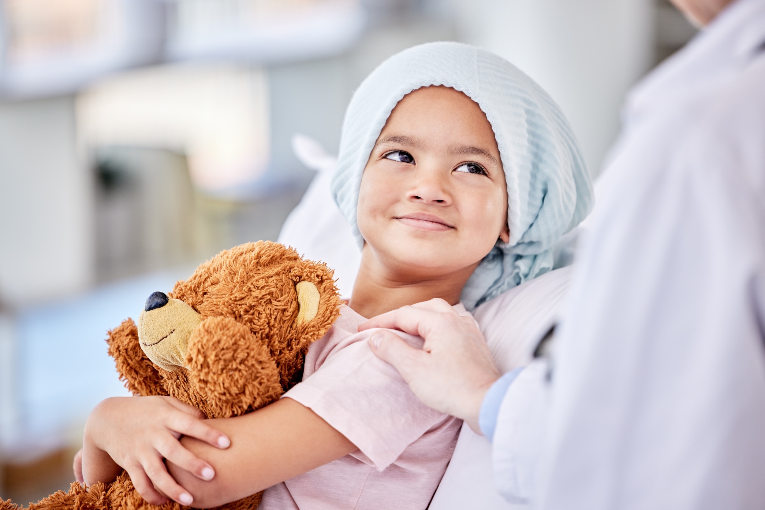 Young girl in hospital with teddy bear receiving treatment for osteosarcoma